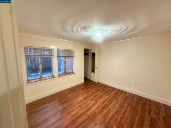a view of an empty room with wooden floor and a window