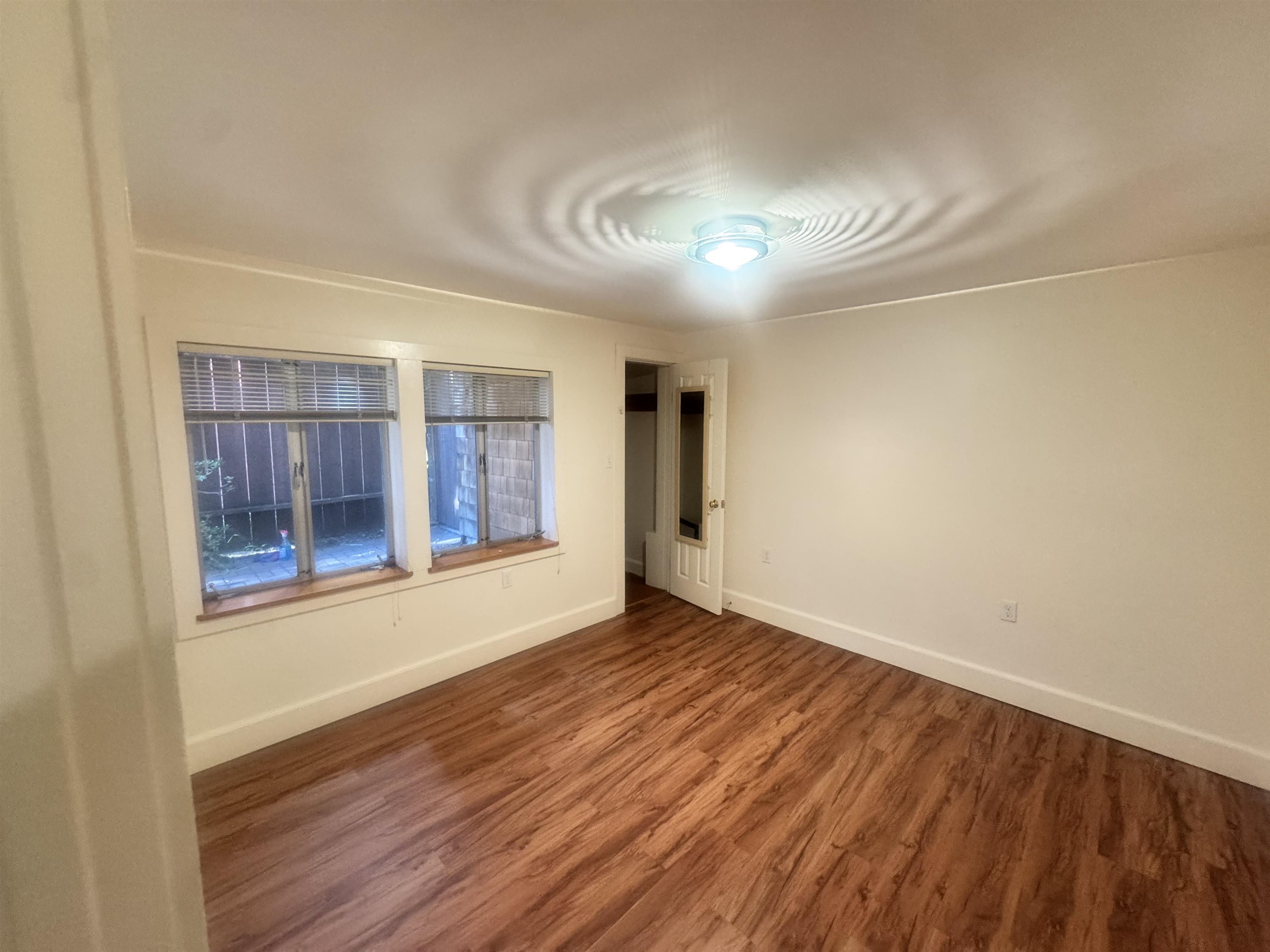 1723 Carleton Street, Unit A Berkeley, CA 94703 - Photo 22 of 32 a view of an empty room with wooden floor and a window