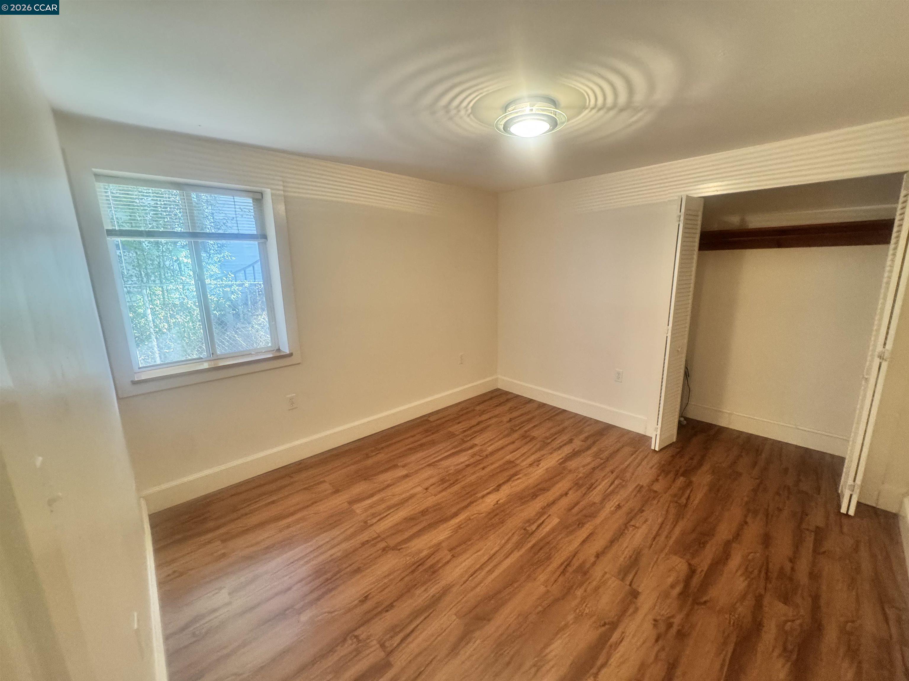 1723 Carleton Street, Unit A Berkeley, CA 94703 - Photo 26 of 32 an empty room with wooden floor and windows