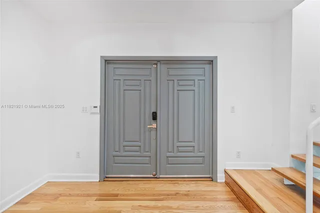 a view of empty room with wooden floor and a window