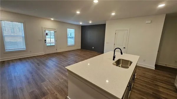 a kitchen that has a lot of cabinets a sink and wooden floor