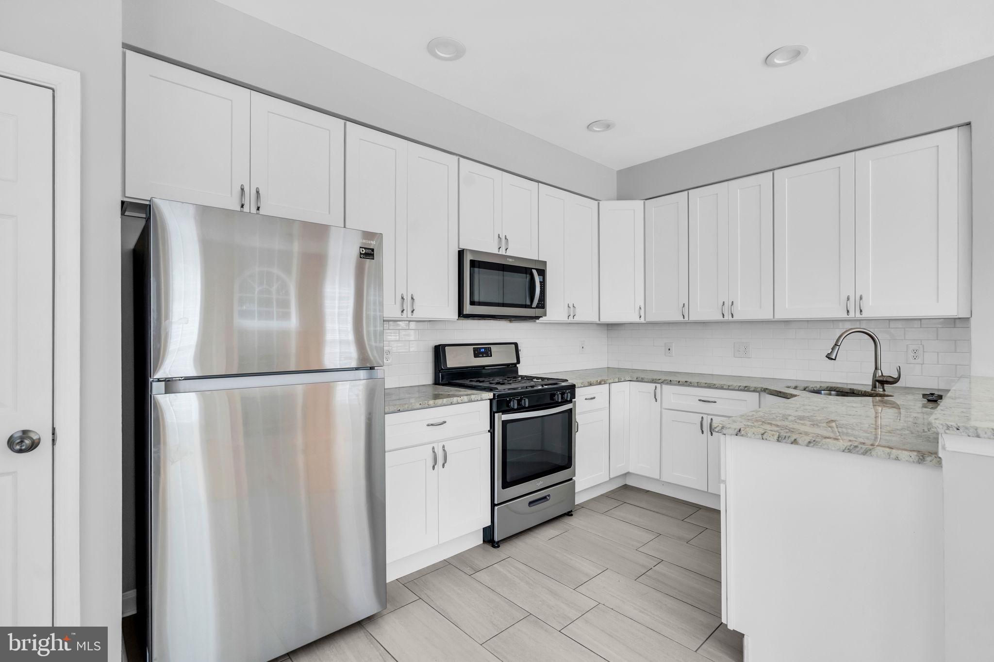 6013 Riddle Walk Alexandria, VA 22312 - Photo 10 of 31 a kitchen with stainless steel appliances granite countertop a refrigerator stove a sink and white cabinets