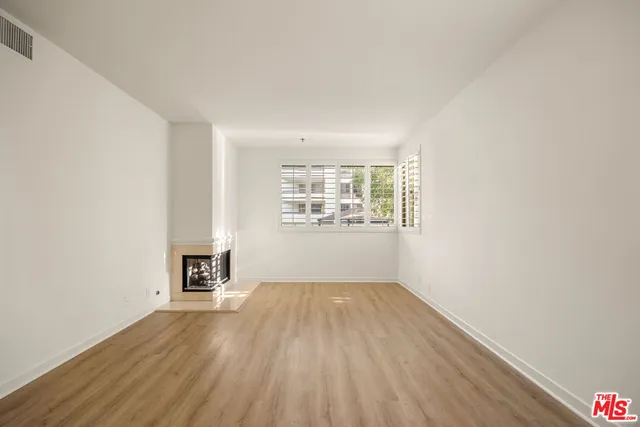 an empty room with wooden floor white walls and windows