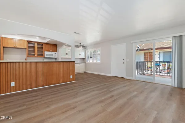 a view of an empty room with wooden floor and windows