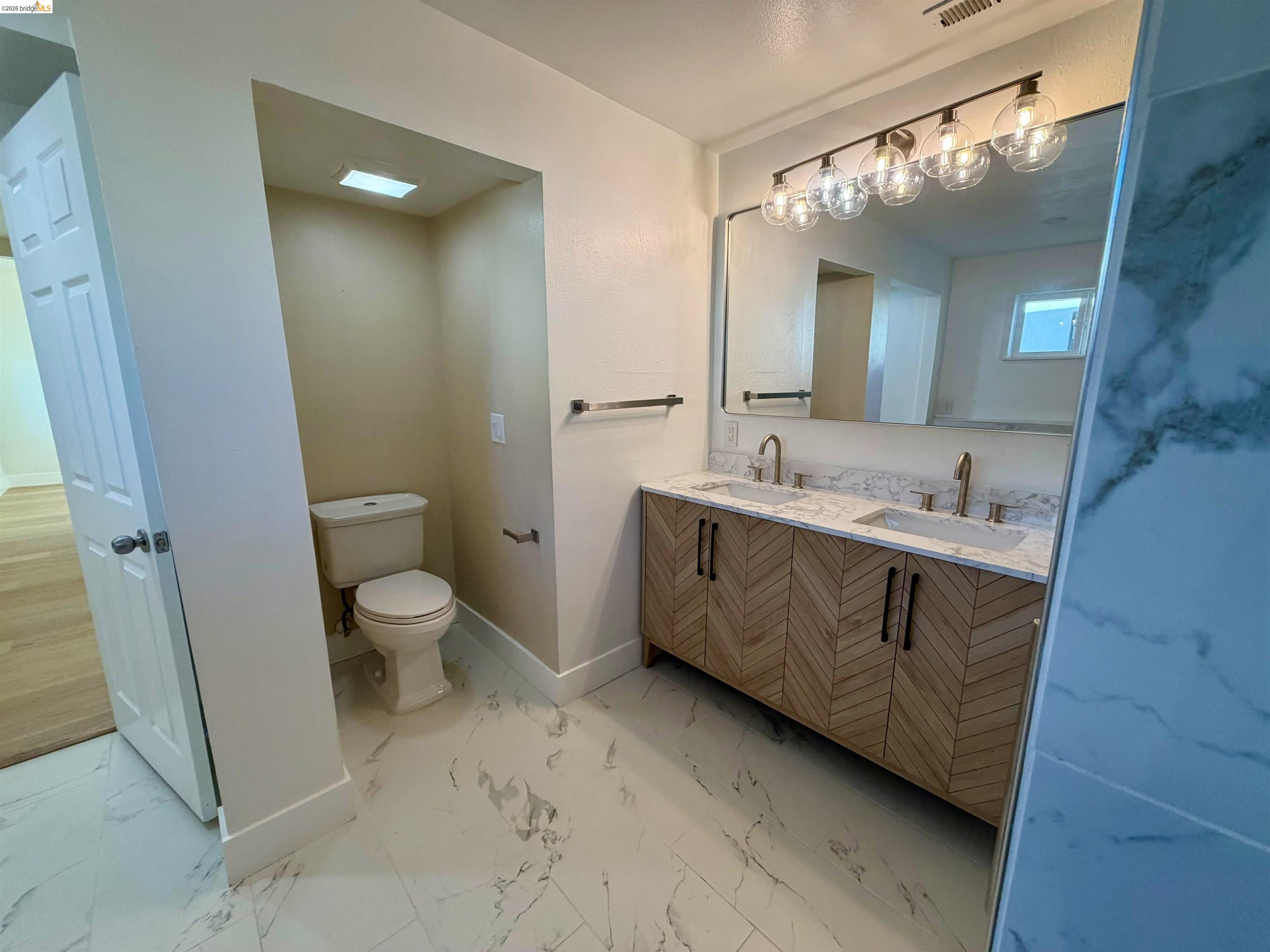1327 Ward Street Berkeley, CA 94702 - Photo 3 of 8 a spacious bathroom with a granite countertop sink mirror vanity and toilet