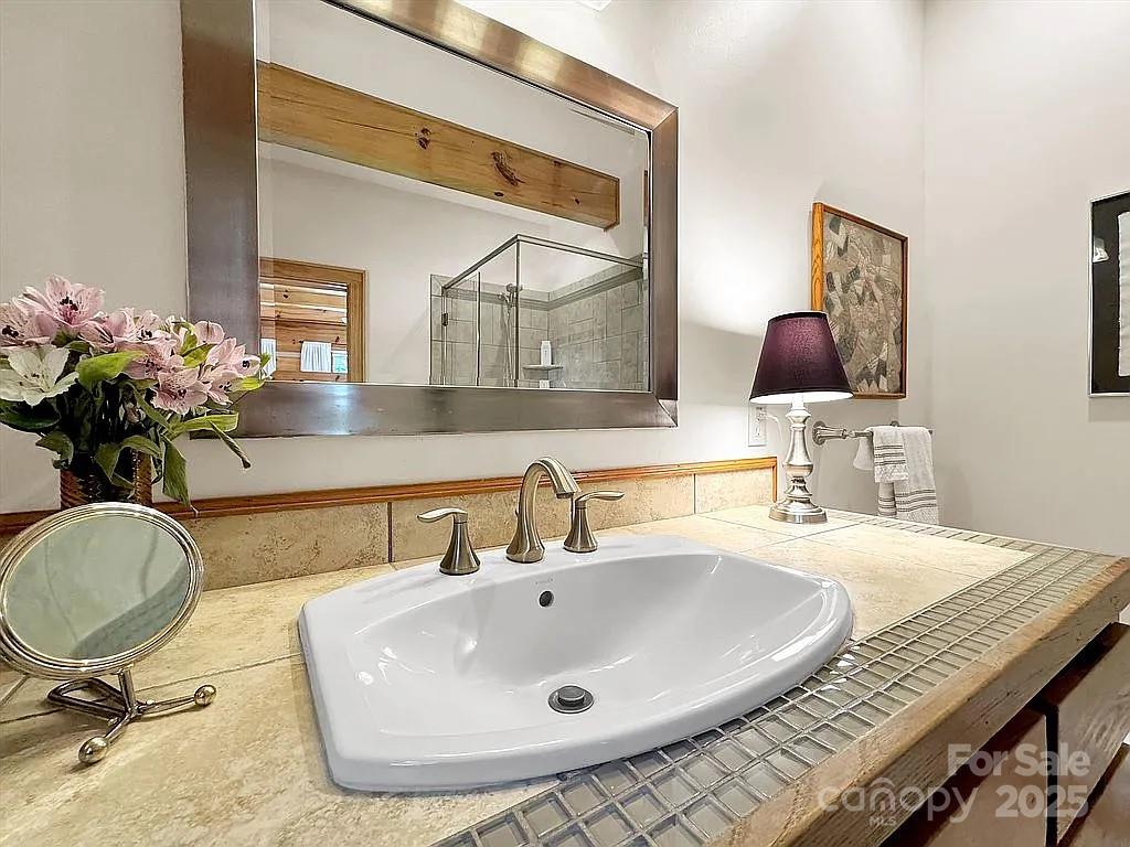 113 Mountain Cove Road Waynesville, NC 28786 - Photo 29 of 48 a bathroom with a granite countertop sink a mirror and vanity