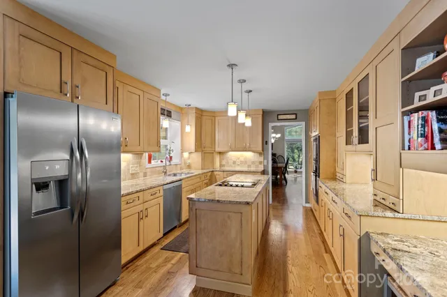 a kitchen with stainless steel appliances granite countertop a refrigerator a stove and a wooden floors