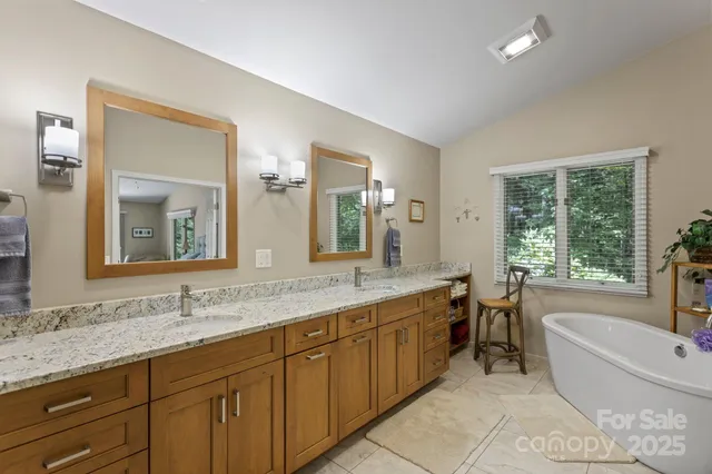 a bathroom with a granite countertop tub double vanity sink and a large mirror