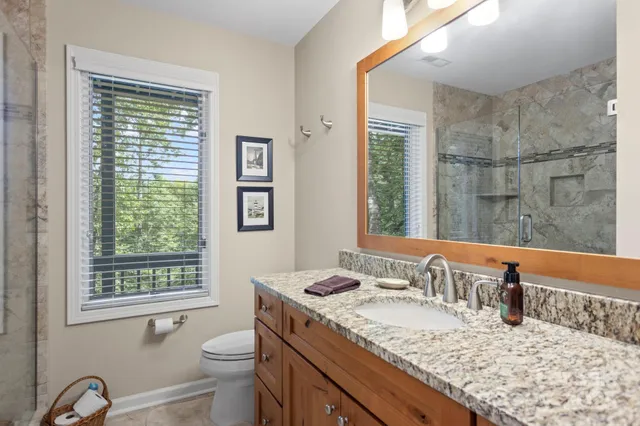 a bathroom with a granite countertop sink mirror vanity and next to a window