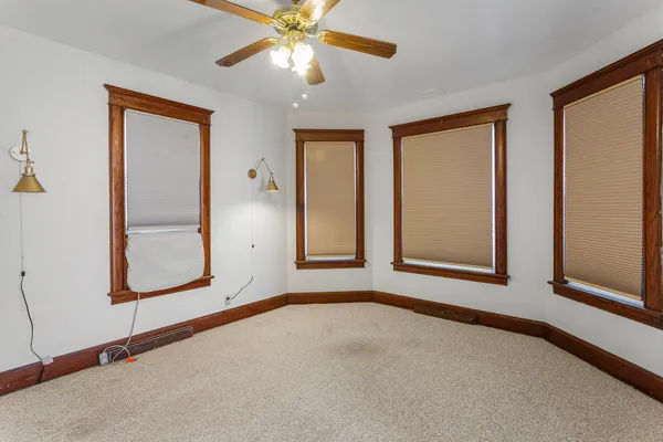 an empty room with windows and fan