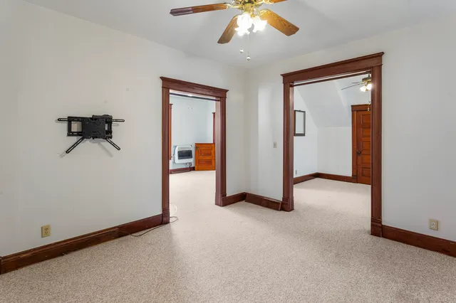 an empty room with chandelier fan and windows