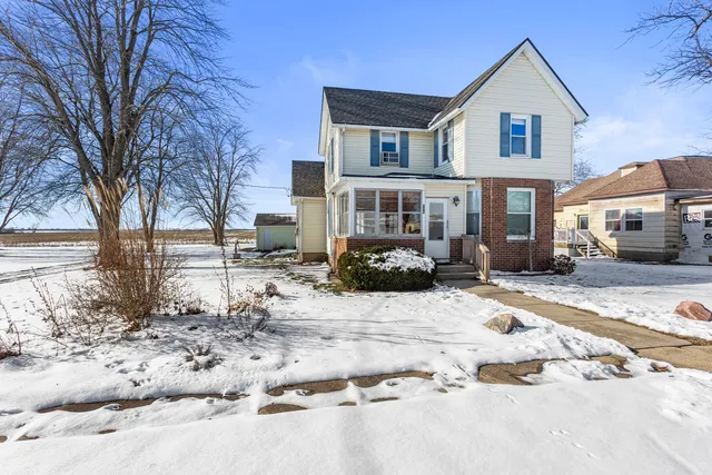 a front view of a house with a yard covered in snow