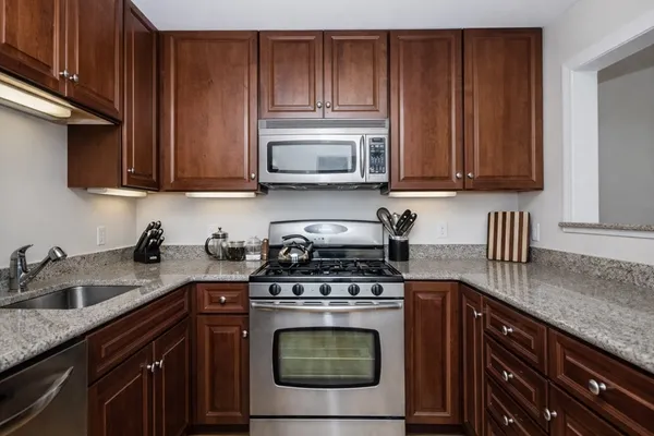 a kitchen with granite countertop wood cabinets and stainless steel appliances