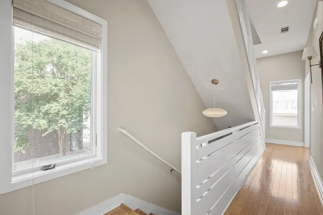 a view of hallway with window and wooden floor