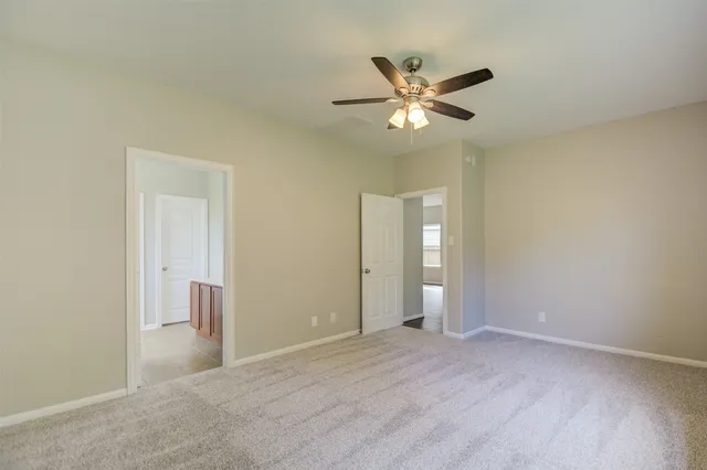 a view of an empty room and chandelier fan