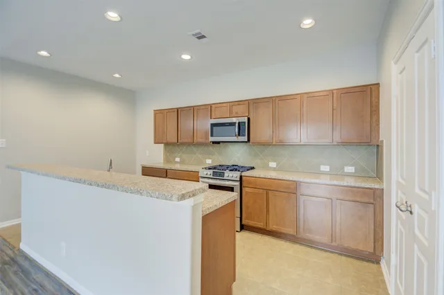 a kitchen with stainless steel appliances granite countertop a stove a sink and a microwave