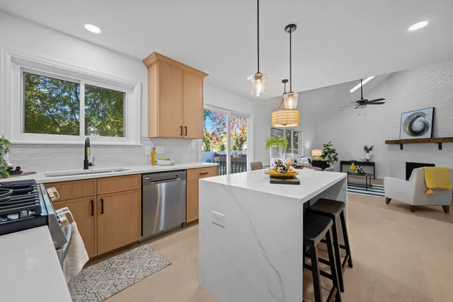 a kitchen with kitchen island granite countertop wooden cabinets a sink a stove and a refrigerator