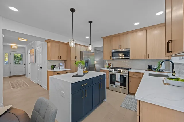 a kitchen with stainless steel appliances granite countertop a stove top oven a sink dishwasher a refrigerator and a dining table with wooden floor