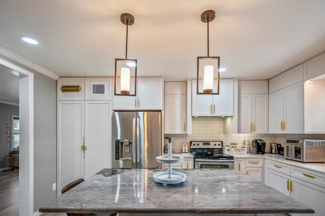 a kitchen with stainless steel appliances granite countertop a refrigerator a stove a sink dishwasher and white cabinets with wooden floor