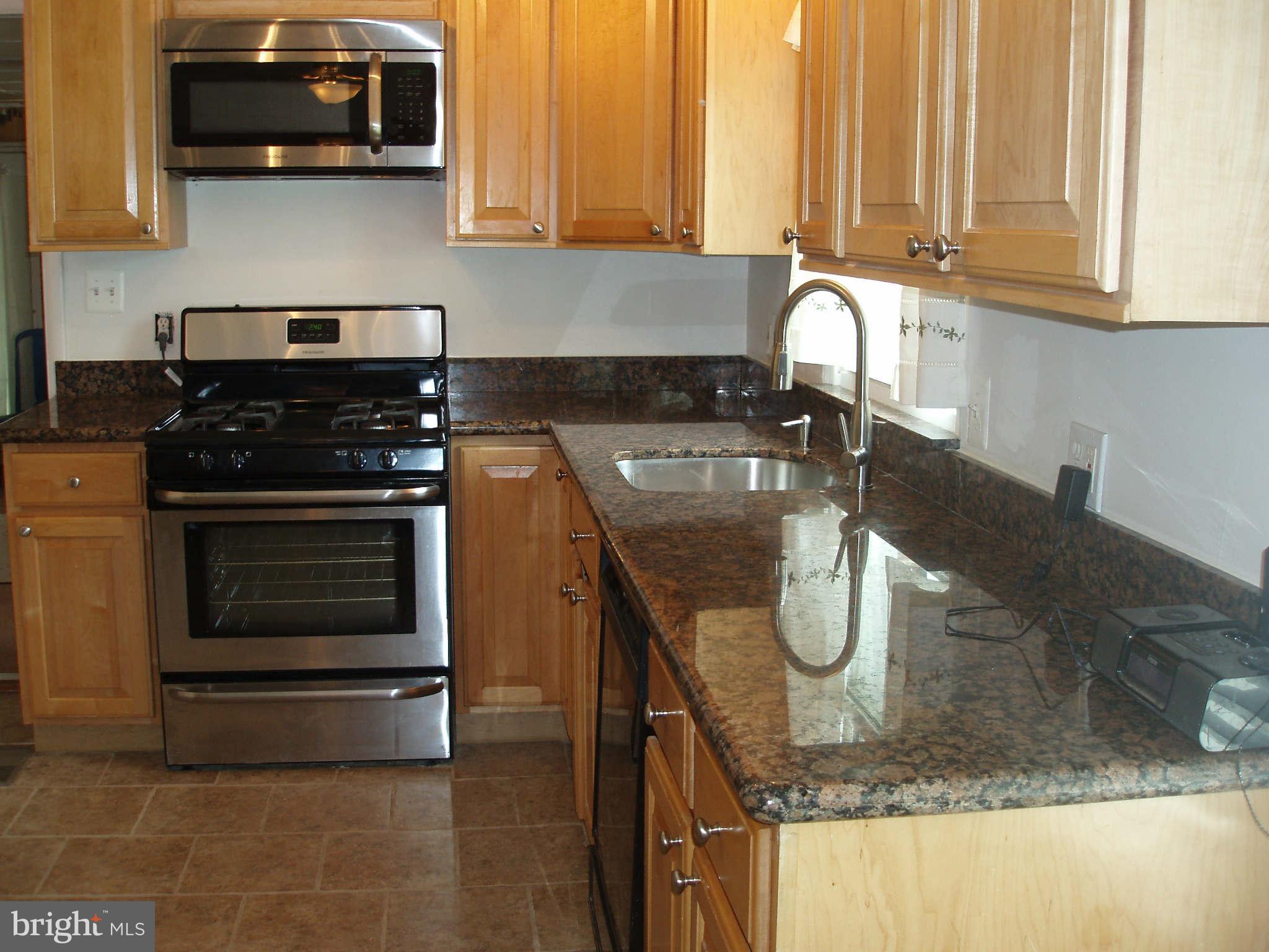 200 Cox Road Huntingtown, MD 20639 - Photo 2 of 27 a kitchen with granite countertop a stove a sink and a microwave