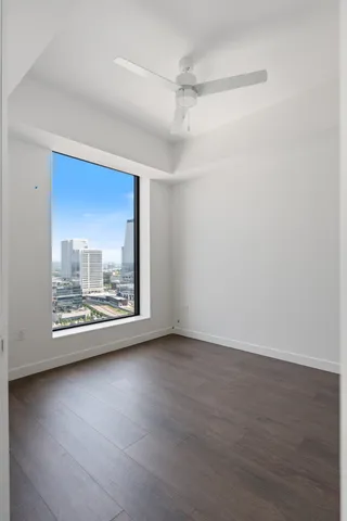 a view of an empty room with wooden floor and a window