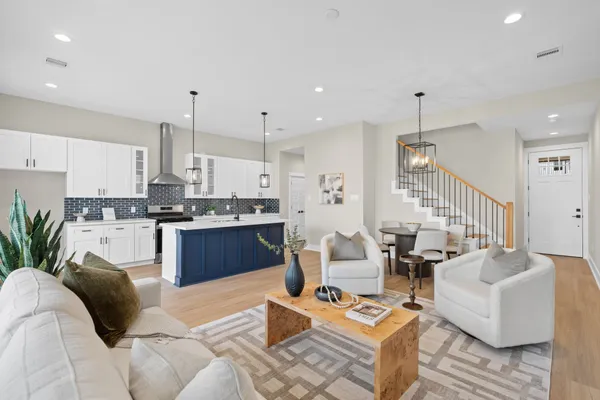 a living room with couches and kitchen view with wooden floor
