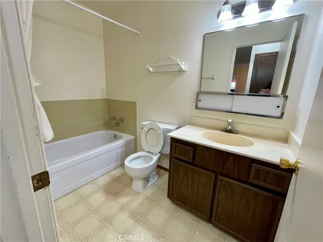 a bathroom with a sink vanity mirror bathtub and toilet