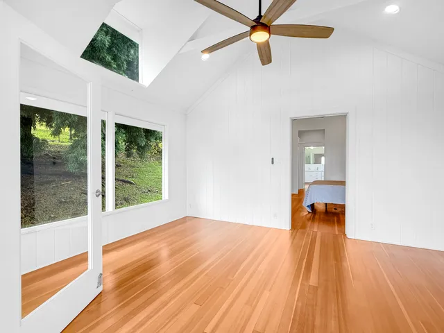 a bedroom with wooden floor a ceiling fan and window