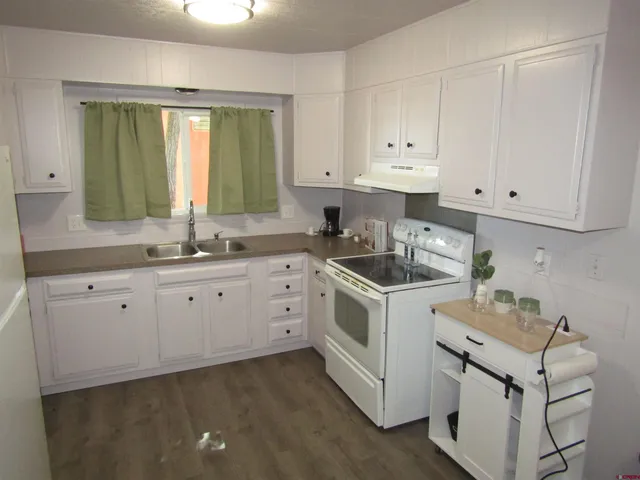 a kitchen with granite countertop white cabinets and white appliances
