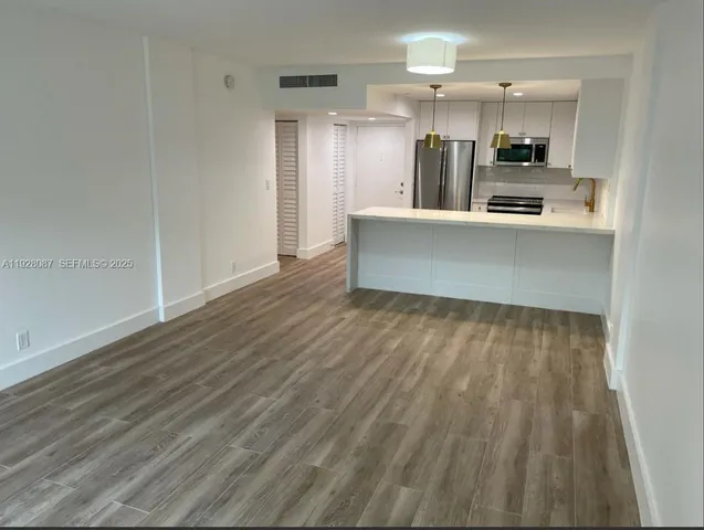 a view of a kitchen with kitchen island wooden floors and stainless steel appliances