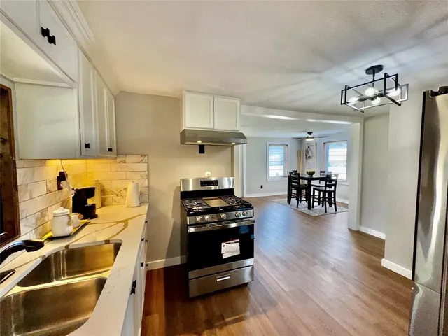a kitchen with wooden floors and white stainless steel appliances