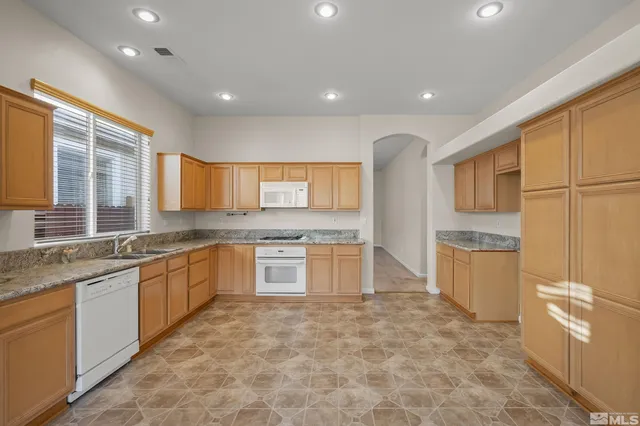 a large kitchen with stainless steel appliances granite countertop a sink and dishwasher a refrigerator