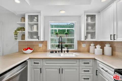 a kitchen with granite countertop a sink a window and cabinets