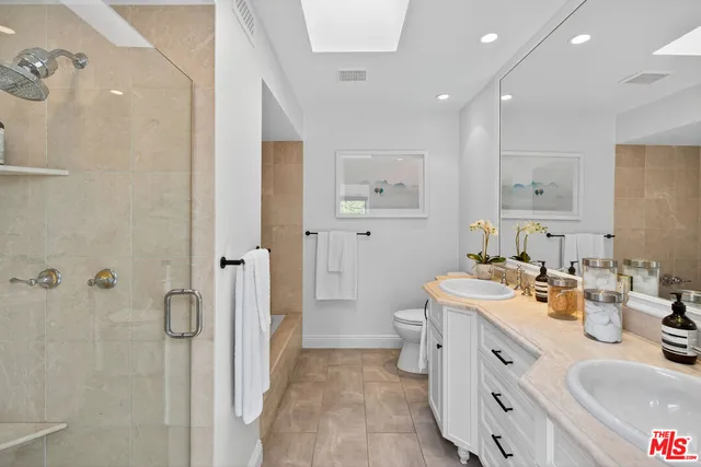 a bathroom with a double vanity sink mirror and shower