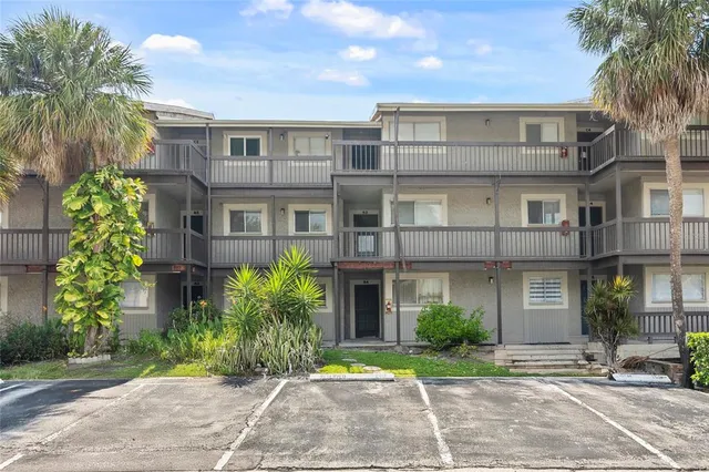 a front view of a residential apartment building with a yard and potted plants
