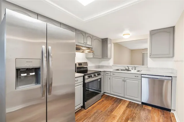 a large kitchen with a sink stainless steel appliances and cabinets