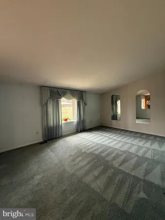 a view of an empty room with window and closet area
