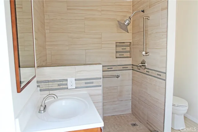 a bathroom with a granite countertop sink a toilet and shower