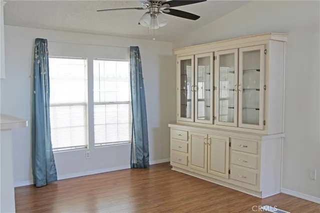 an empty room with wooden floor cabinet and windows