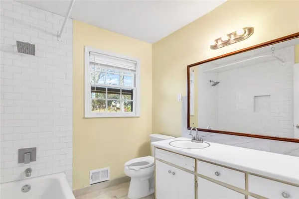 a bathroom with a toilet a sink a tub and mirror