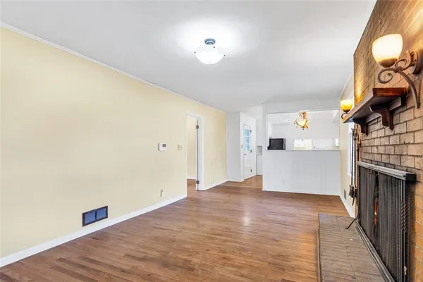 a view of empty room with wooden floor and fireplace