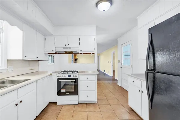 a kitchen with white cabinets and refrigerator