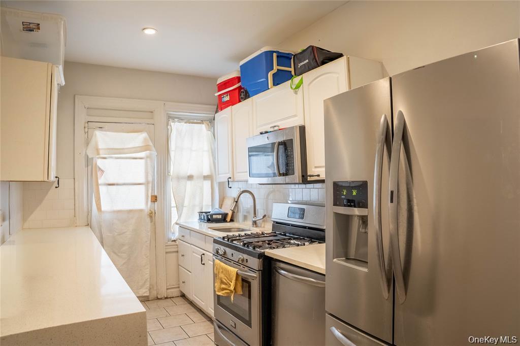 33-26 83rd Street Queens, NY 11372 - Photo 5 of 18 a kitchen with stainless steel appliances granite countertop a refrigerator a stove and a sink with wooden floor
