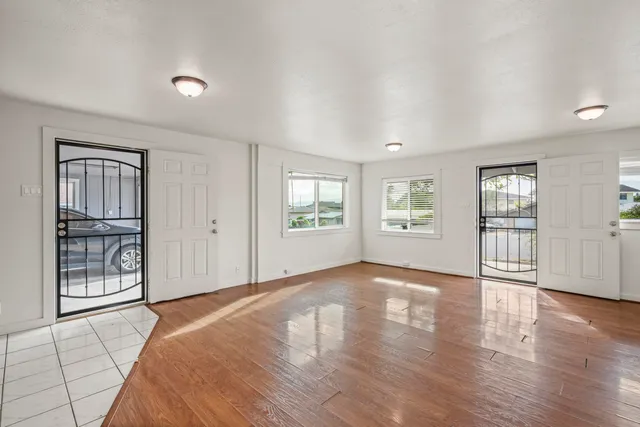 a view of an empty room with wooden floor and windows
