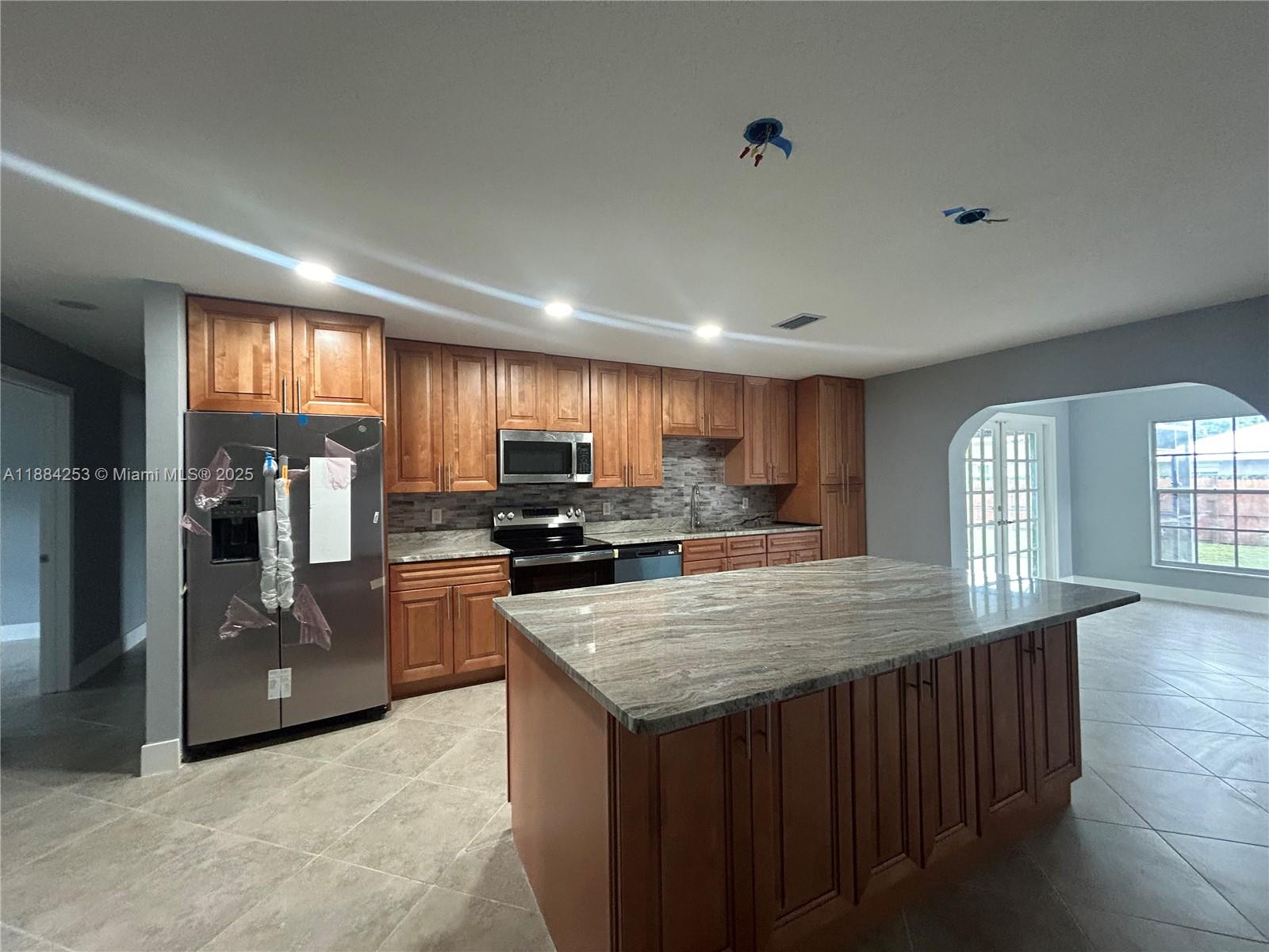 7109 Santa Rosa Parkway Fort Pierce, FL 34951 - Photo 4 of 11 a kitchen with stainless steel appliances granite countertop a refrigerator a sink dishwasher a oven a large countertops with wooden cabinets and floor