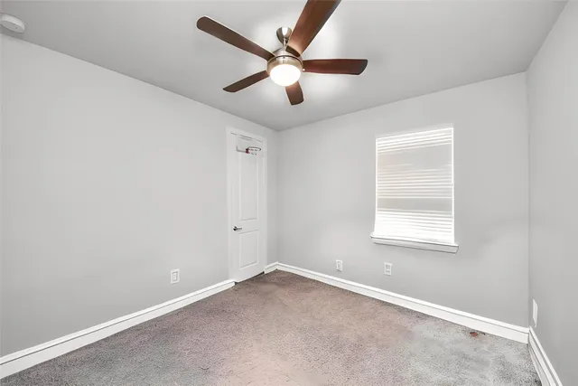 an empty room with wooden floor ceiling fan and windows