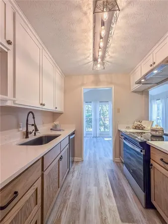 a kitchen with granite countertop a sink cabinets stainless steel appliances and a counter top space