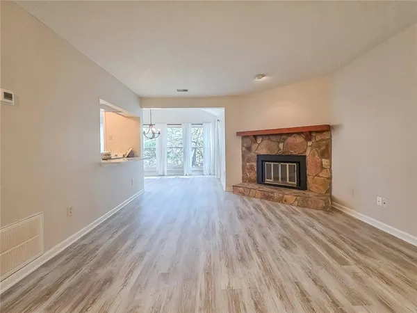 an empty room with wooden floor fireplace and windows