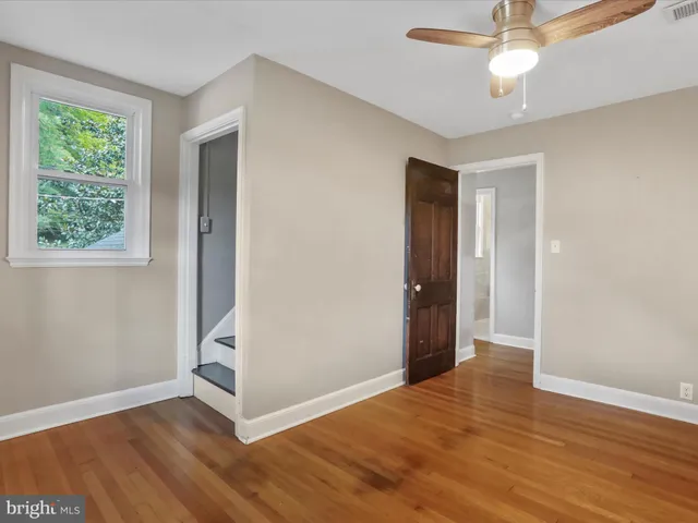 an empty room with wooden floor chandelier fan and windows