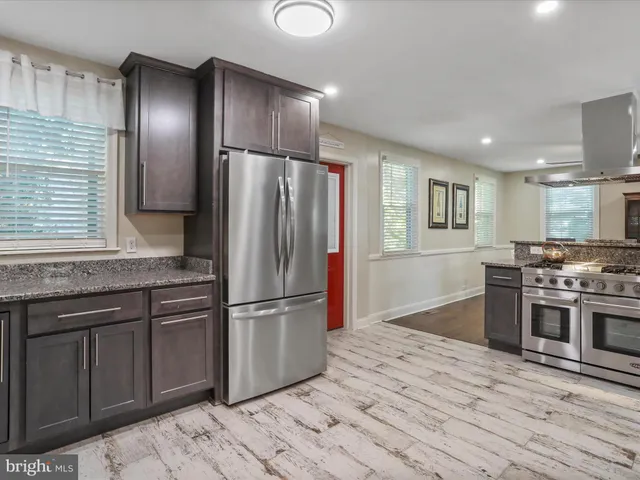 a kitchen with stainless steel appliances granite countertop a refrigerator and a stove top oven